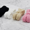 Four pairs of unique shoelaces that are fuzzy are displayed on a marble countertop by Fleece Chic.