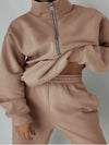 Camel colored fleece loungewear with matching sweatshirt and sweatpants are worn by a woman who is holding up the top to expose her midriff - Fleece Chic