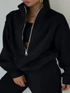 A black tracksuit with matching sweatshirt and sweatpants are worn by a woman who is posing for the camera - Fleece Chic