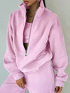 A pink tracksuit with matching sweatshirt and sweatpants are worn by a woman who is posing for the camera - Fleece Chic