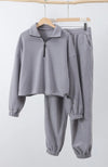 A matching set of gray sweats clothing is hung up on wooden hangers - Fleece Chic