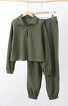 A matching set of green sweats clothing is hung up on wooden hangers - Fleece Chic