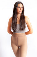 A Hispanic woman wearing tan pantyhose and a gray crop top poses for a photograph with her arms behind her - Fleece Chic