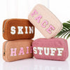 Soft bags for makeup or toiletries with chenille patches are stacked up to display their different variations - Fleece Chic