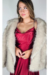 Fox fur coat by Fleece Chic is worn by a woman in a red silk dress who is loking off camera.