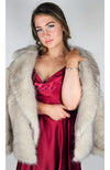 Fox fur coat by Fleece Chic is worn by a woman in a red silk dress.