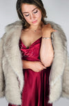 Fox fur coat by Fleece Chic is worn by a woman in a red silk dress.