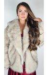 Fox fur coat by Fleece Chic is worn by a woman in a red silk dress who has long brown hair.