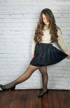 A high waist pleated skirt that is black is worn by a woman in faux translucent fleece tights and heels making a funny pose - Fleece Chic