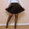 A black skater skirt is worn by a woman in thermal pantyhose and heels holding out her skirt in a curtsy-like pose - Fleece Chic