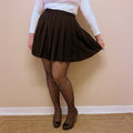 A high waist pleated skirt that is black is worn by a woman in cozy tights and heels - Fleece Chic