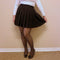 A high waist pleated skirt that is black is worn by a woman in cozy tights and heels - Fleece Chic