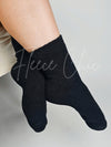 A woman poses in a black pair of boot socks - Fleece Chic
