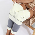 Cozy leggings that are light gray have their soft fleece lining tugged by a woman in a gold metalic dress - Fleece Chic